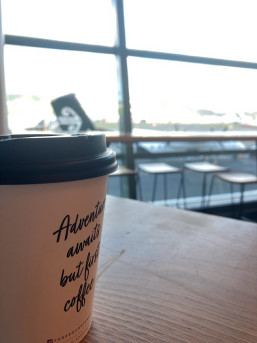 Coffee cup at the airport saying Adventures Ahead